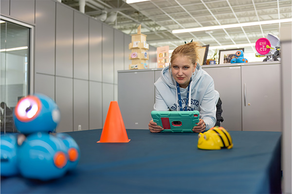 A student demonstrates robots used at CybHER outreach events.